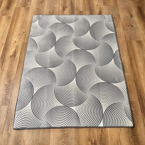 A soft, light gray foam rug with a modern pattern